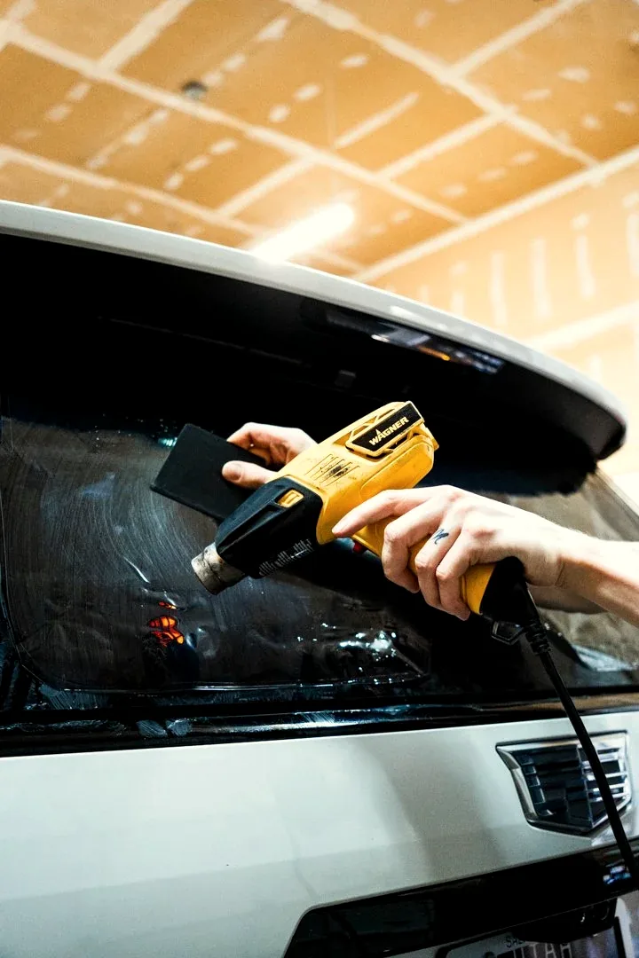 Heat gun shrinking window film on a rear windshield