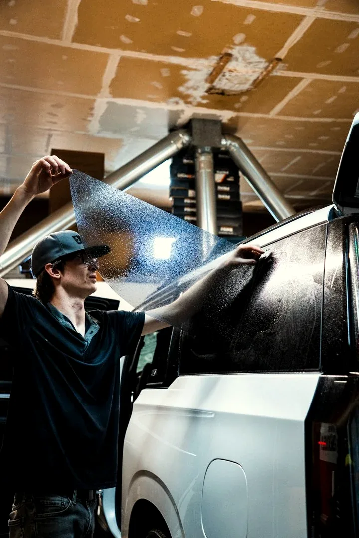 Landon holding a sheet of window film in the shop